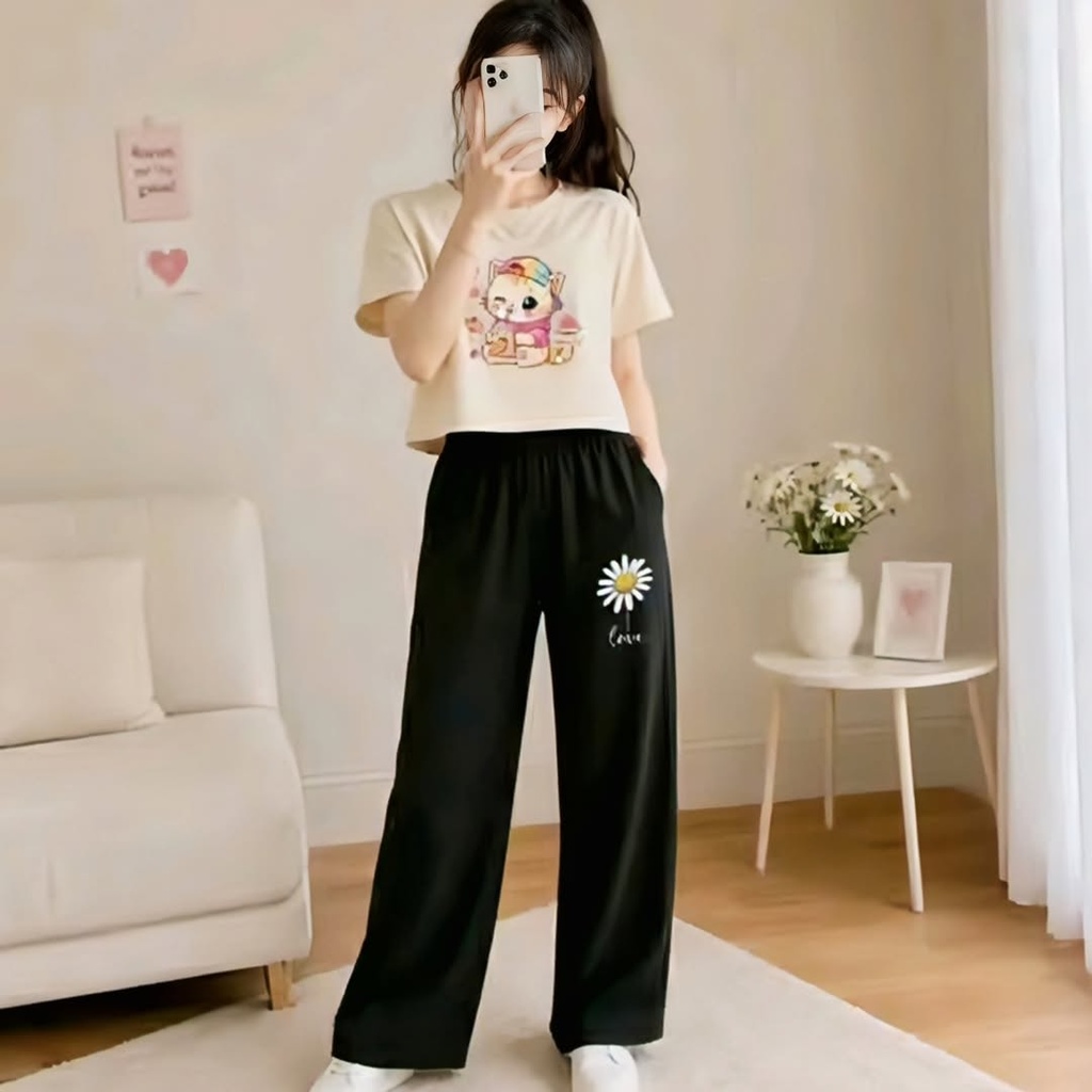 A cream crop top with a cartoon cat graphic is paired with Daisy - printed black wide - leg trousers (M)