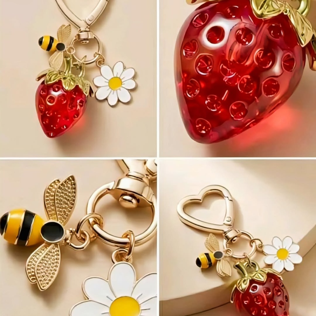 A charming keychain with a red strawberry, a bumblebee and a daisy charm on a golden heart clasp