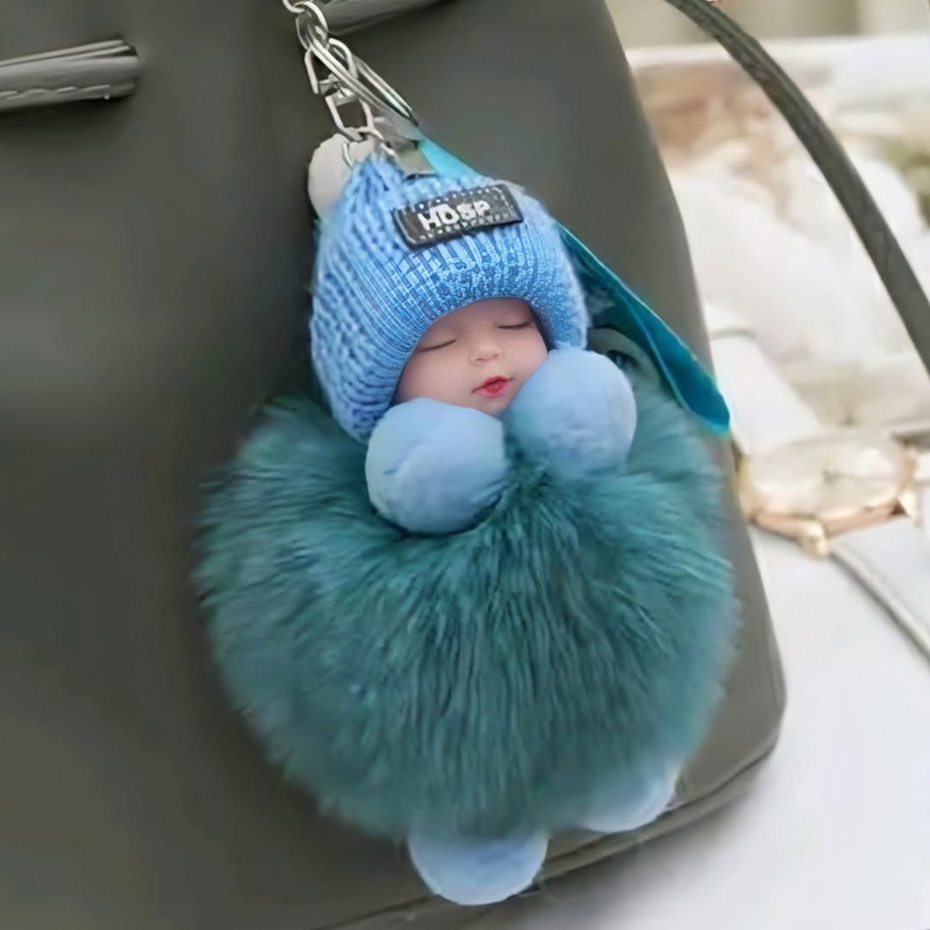A sleeping baby doll keychain wearing a blue knit